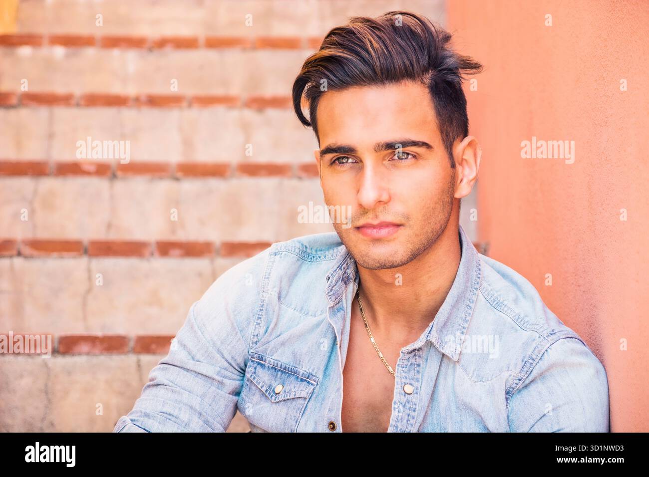 Bel uomo seduto sulle scale mentre guardando la fotocamera Foto Stock