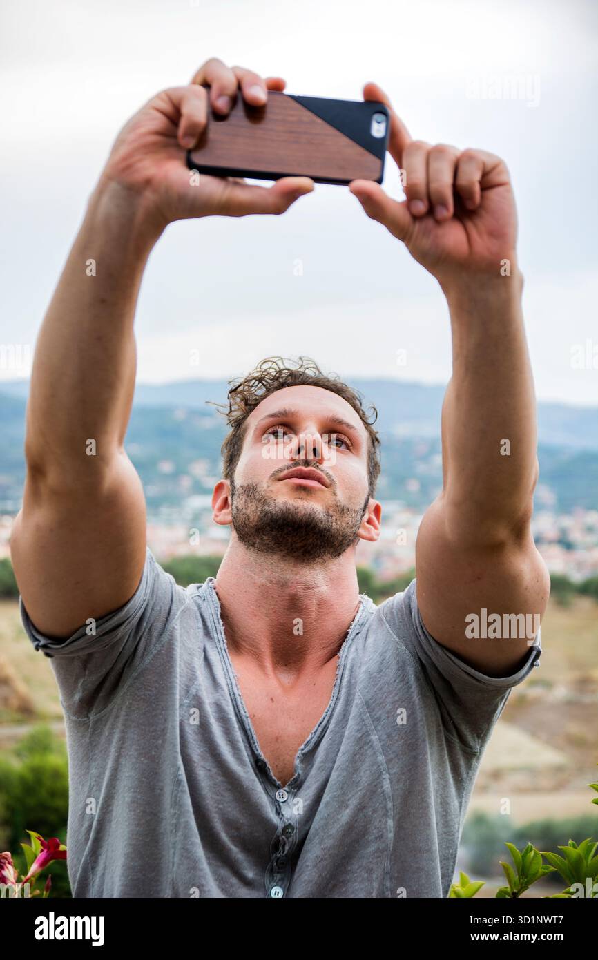 Giovane uomo che porta selfie con cellulare all'aperto Foto Stock