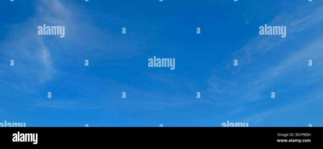 Un cielo blu chiaro e luminoso funge da sfondo semplice e minimalista, con solo sottili nuvole di cirrus ai bordi. Foto Stock
