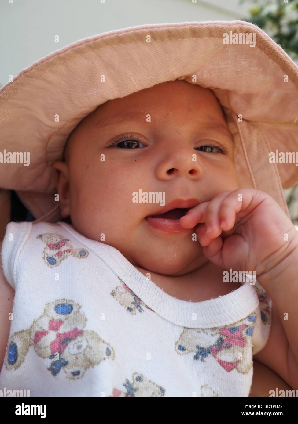 Il bambino indossa un cappello da sole seduto con la madre all'aperto, sorridendo alla luce naturale del sole. Connessione familiare e felicità d'infanzia. Foto Stock