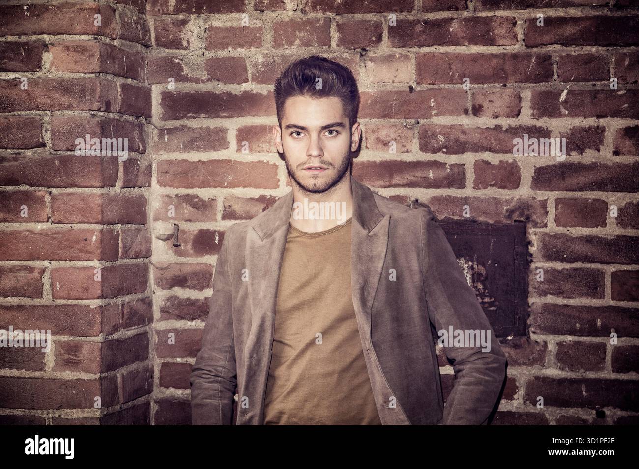 Attraente giovane uomo in piedi contro un muro di mattoni Foto Stock