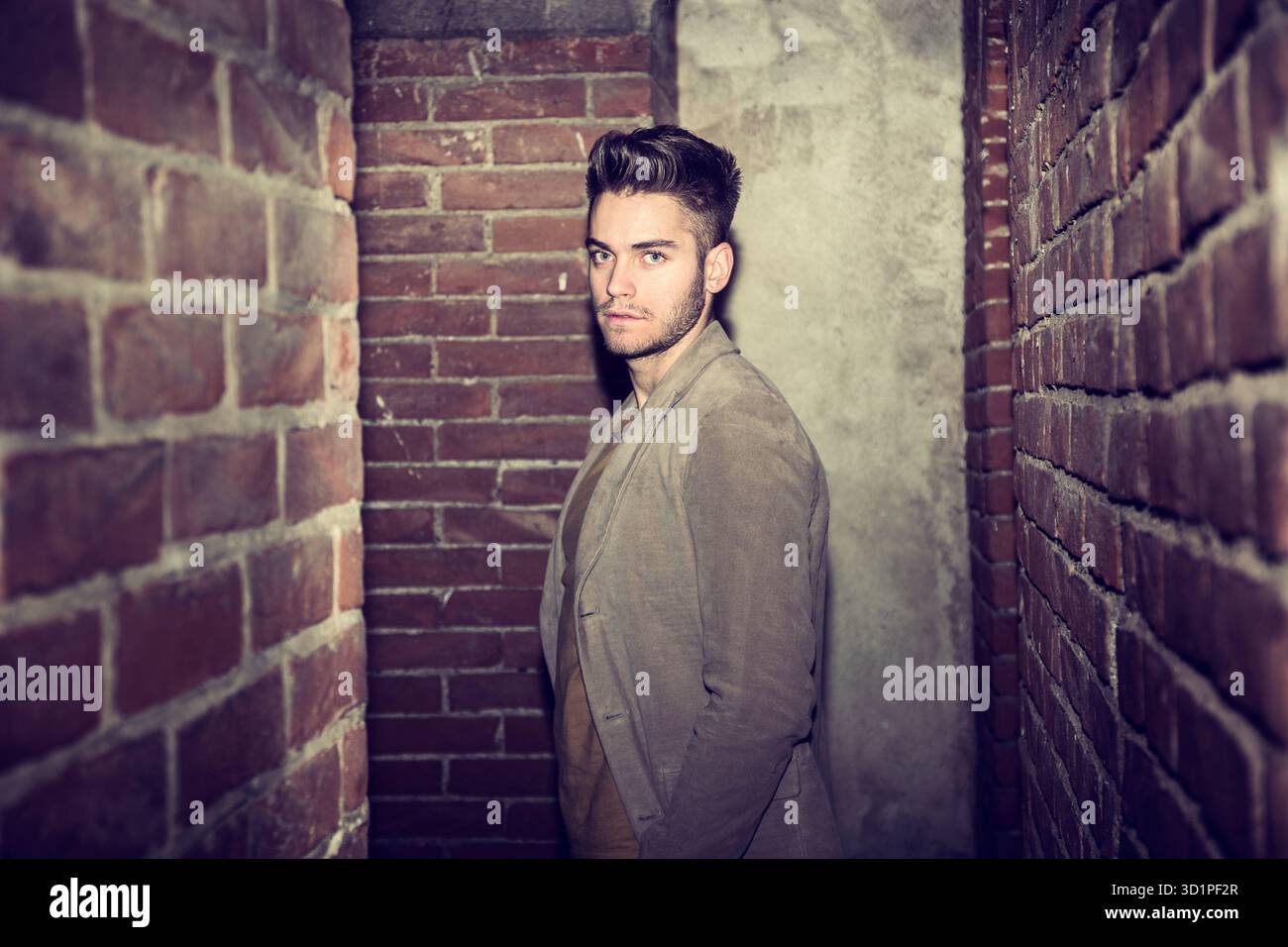 Attraente giovane uomo in piedi contro un muro di mattoni Foto Stock