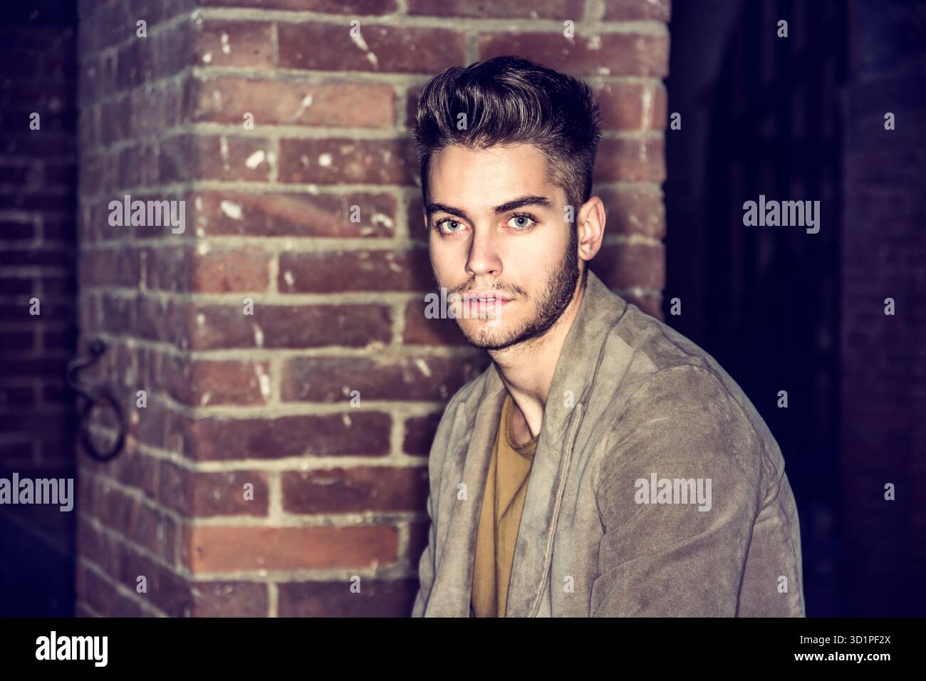 Attraente giovane uomo in piedi contro un muro di mattoni Foto Stock