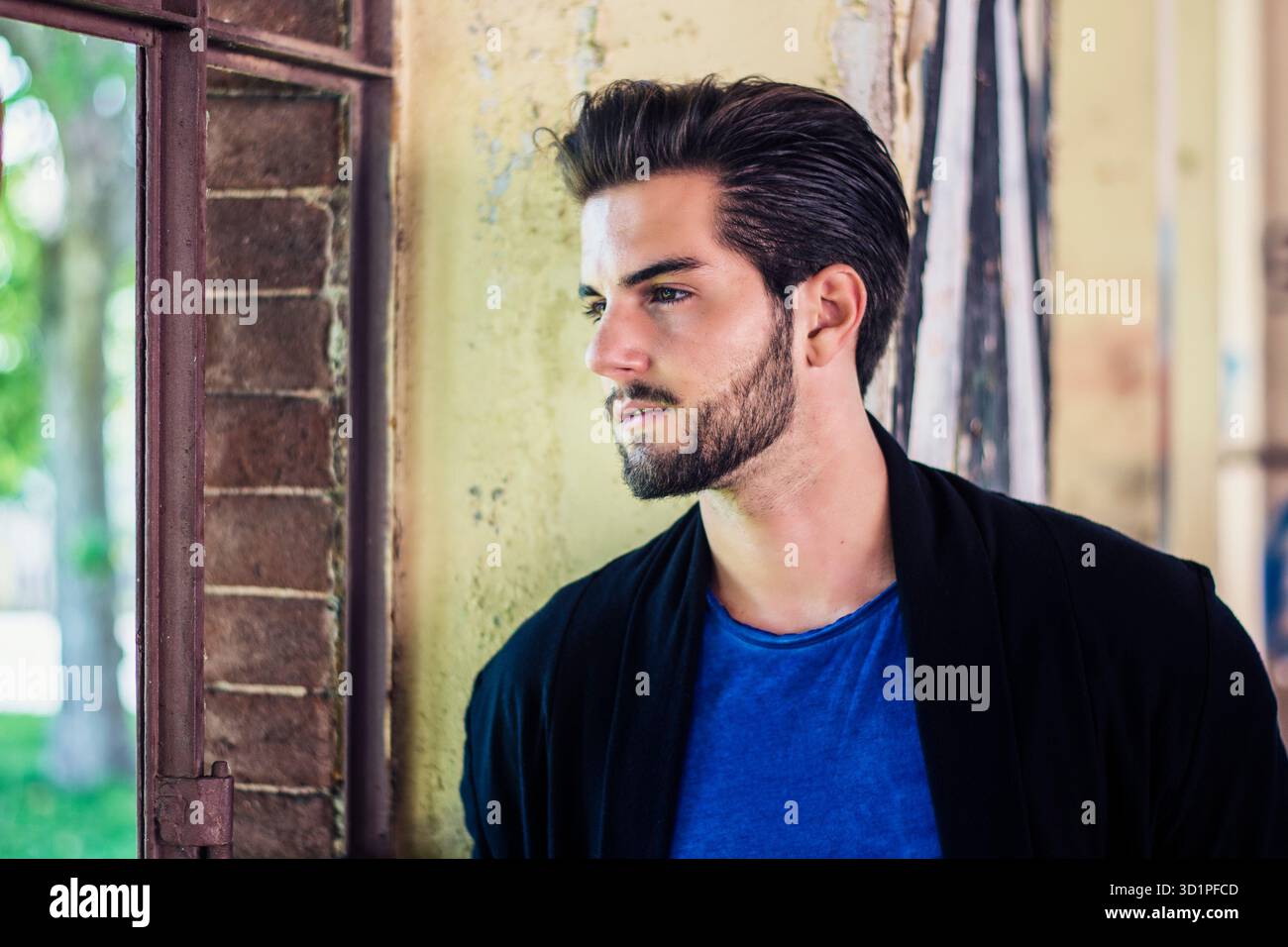 Attraente giovane uomo in piedi contro un muro di mattoni Foto Stock