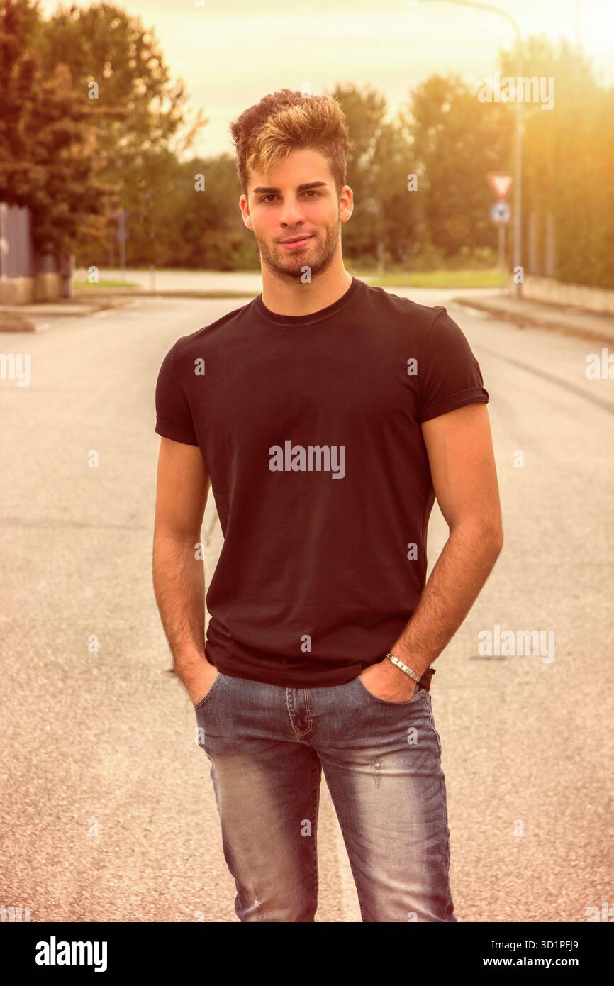 Attraente uomo sorridente in piedi nel centro della strada di città Foto Stock