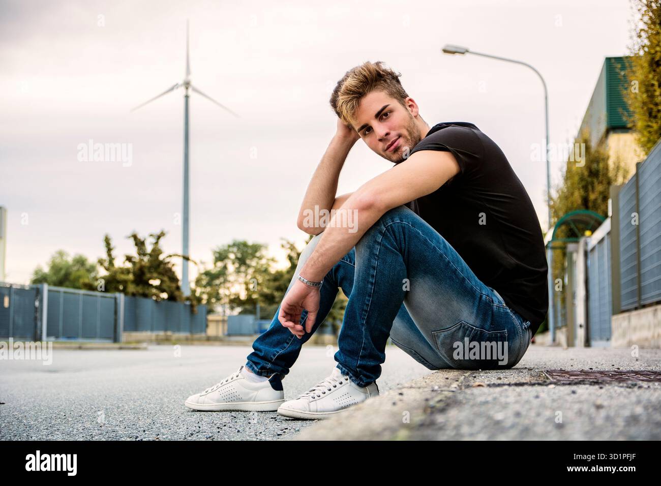 Attraente uomo sorridente seduto da strada di città Foto Stock
