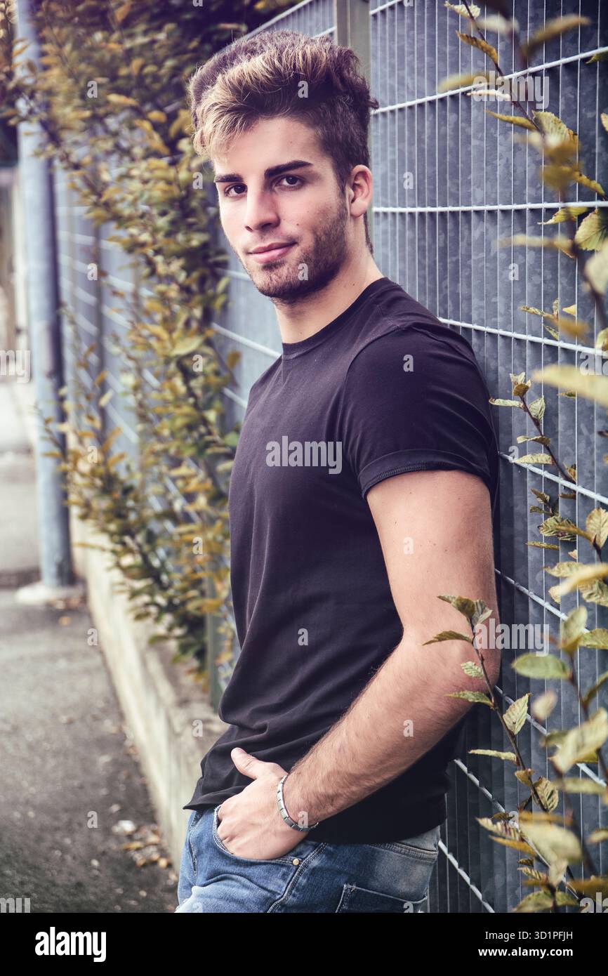Un uomo sorridente attraente in piedi per la strada della città Foto Stock