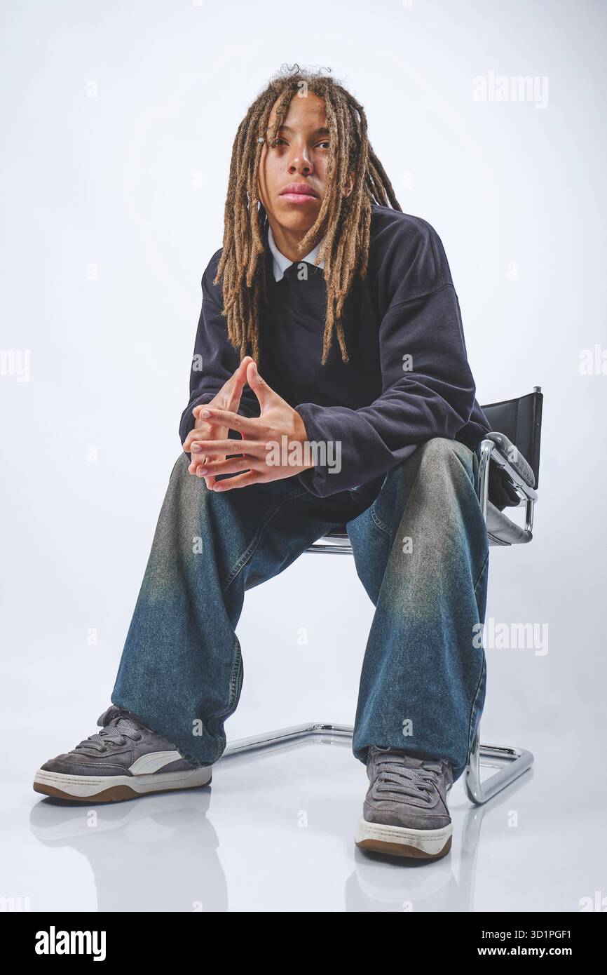 Giovane con dreadlock seduto pensivo in studio Foto Stock