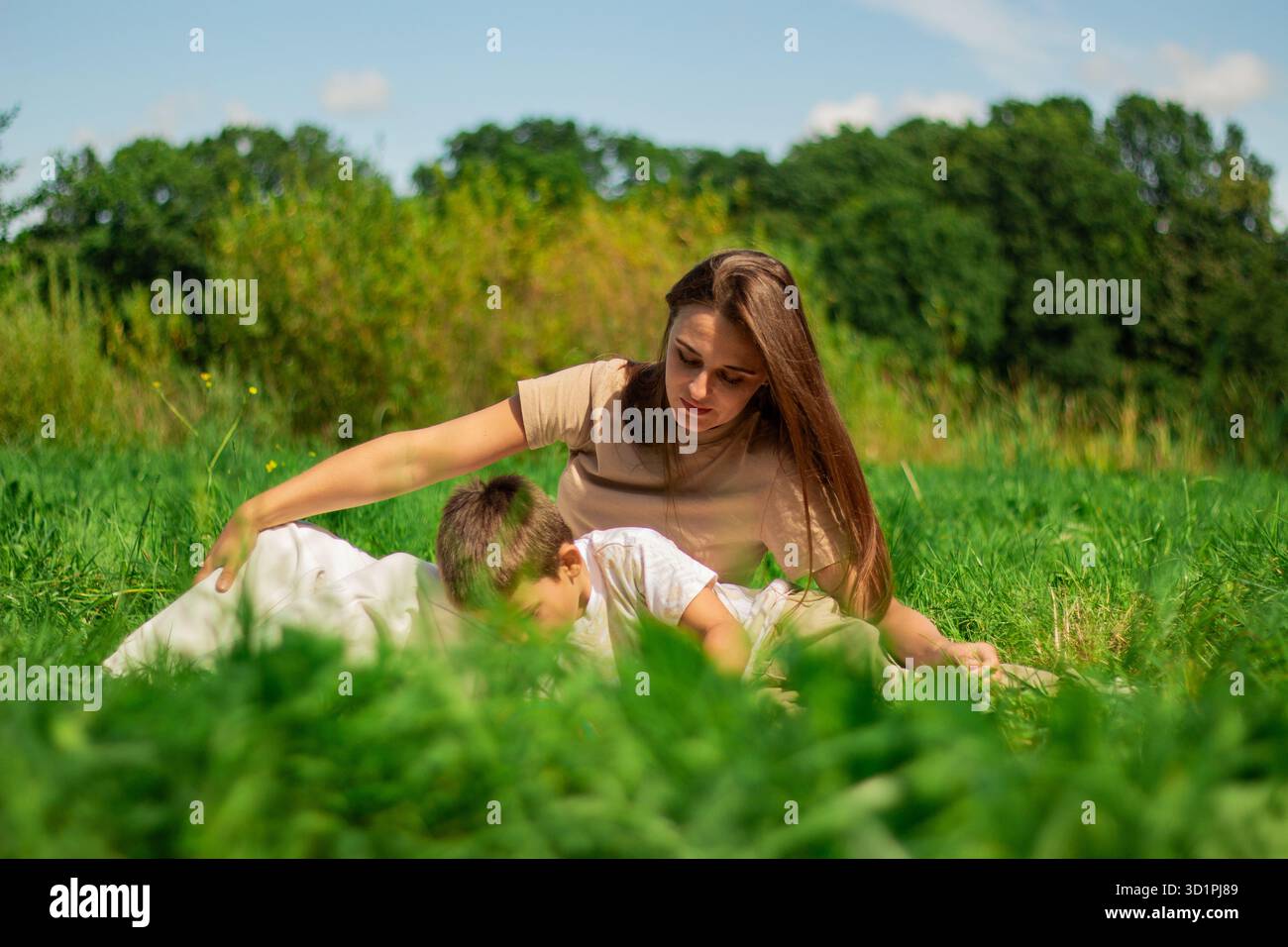 Mamma e suo figlio trascorrono del tempo insieme sulla natura e leggono un interessante libro sui dinosauri. Tempo di qualità con il bambino. Foto Stock