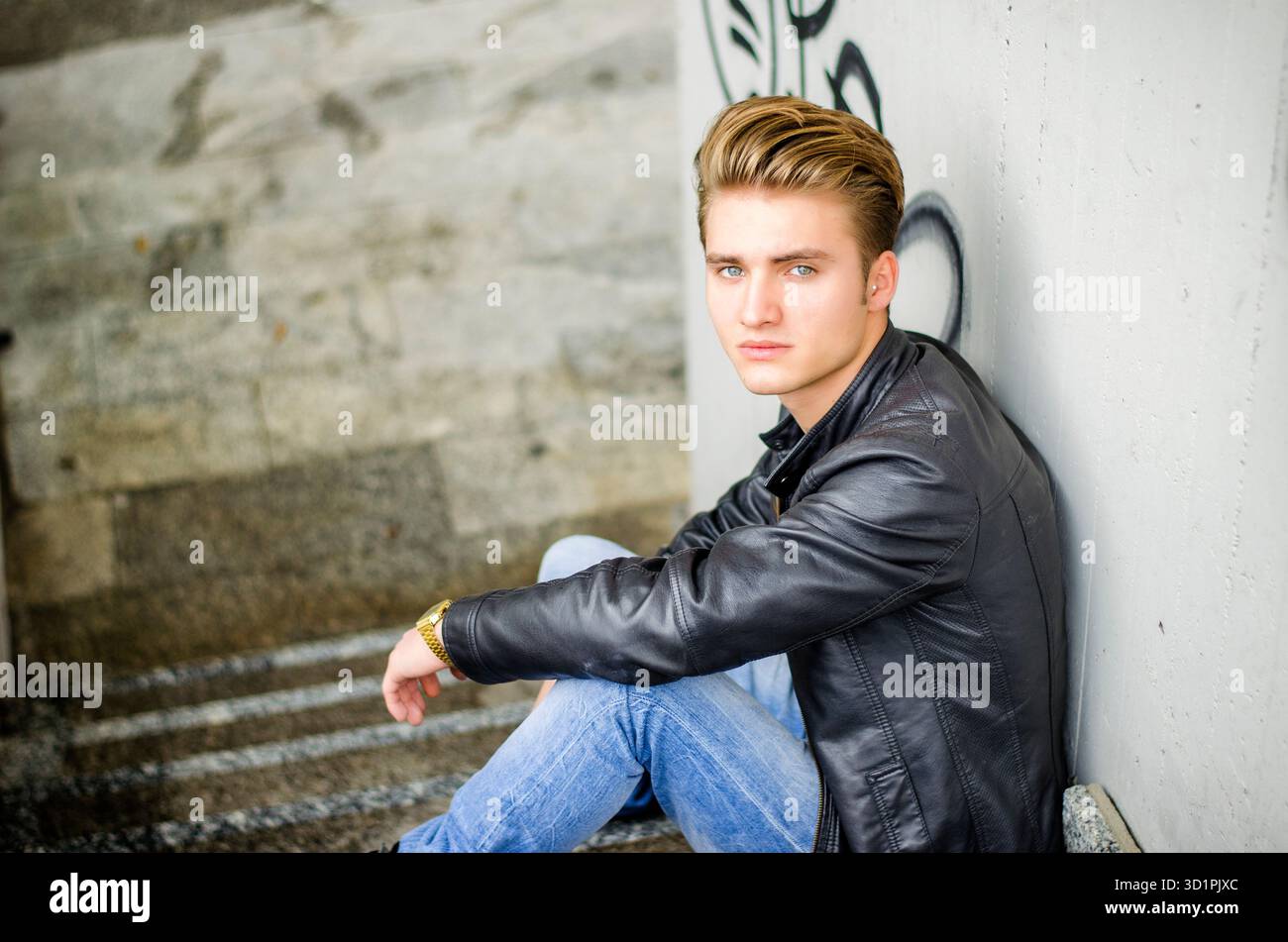 Attraente bionda giovane uomo seduto sulle scale per esterno Foto Stock