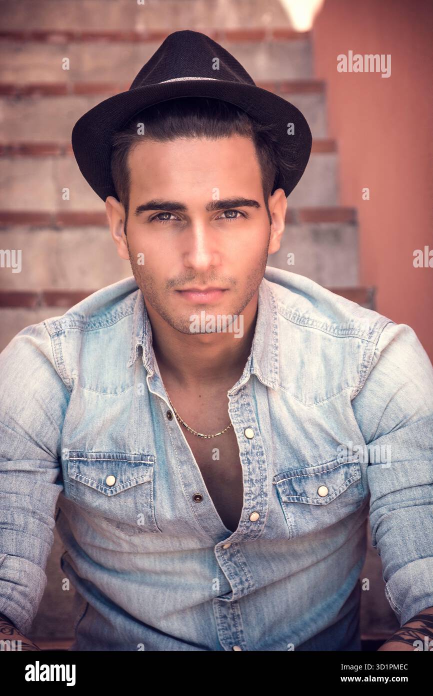 Bel uomo seduto sulle scale mentre guardando la fotocamera Foto Stock