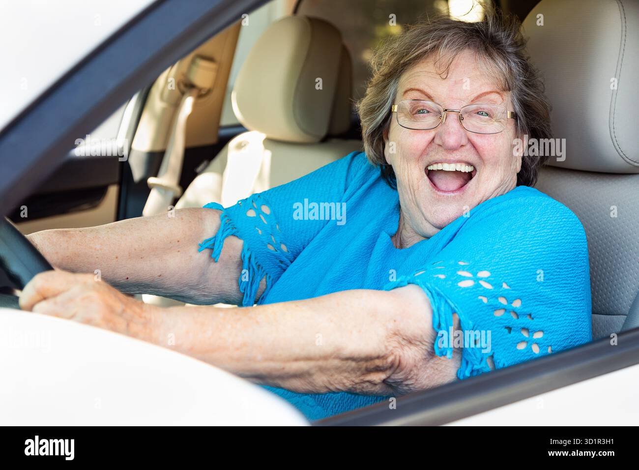 Felice donna anziana alla guida di un'auto nuova Foto Stock