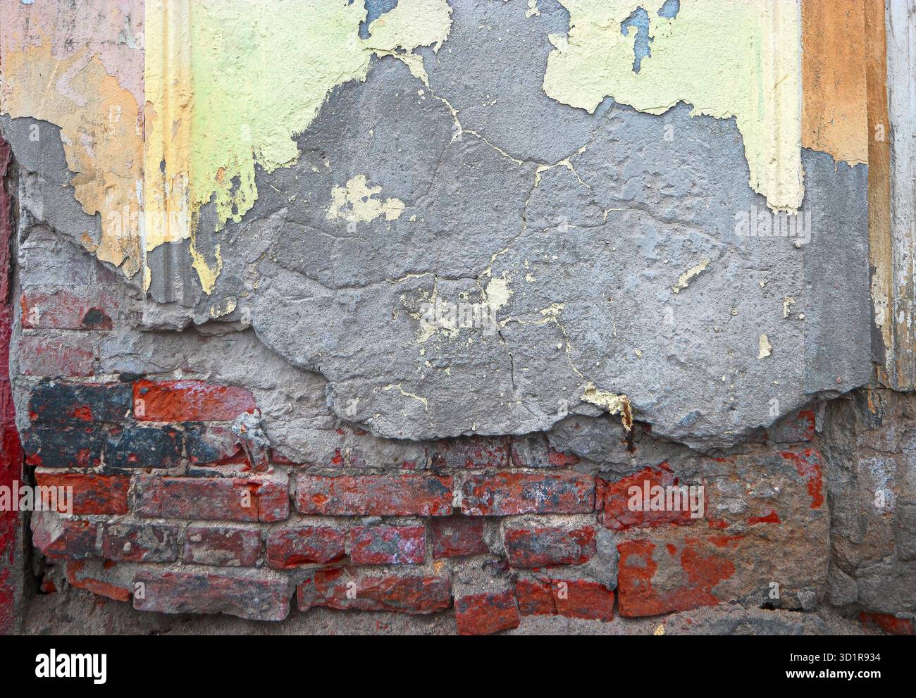 Muratura in mattoni rossi grunge metà ricoperta da vecchio intonaco di colore grigio e giallo Foto Stock
