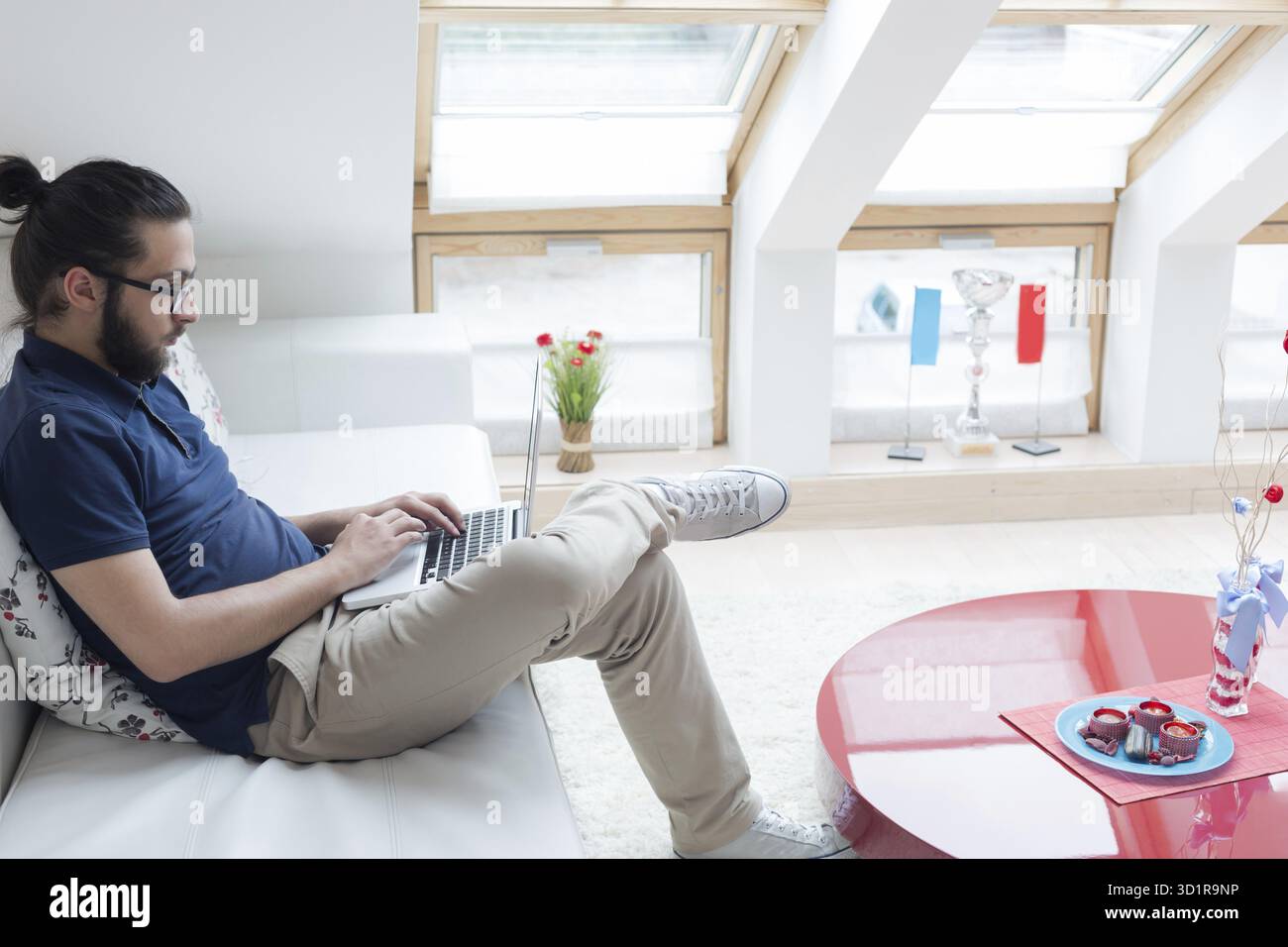 Ritratto di un giovane uomo d'affari in abiti casual presso un moderno ufficio di avvio, che lavora su un computer portatile Foto Stock