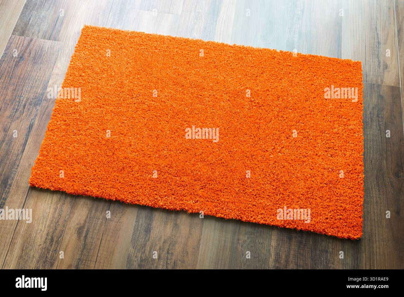 Tappeto di benvenuto arancione vuoto su sfondo pavimento in legno pronto per il tuo testo Foto Stock