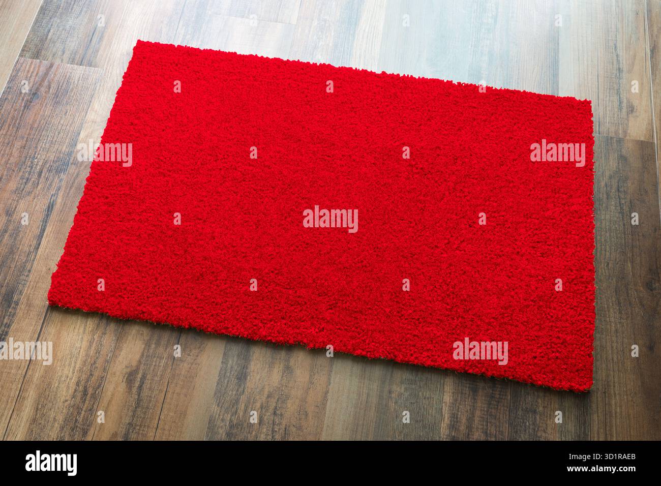 Tappeto di benvenuto rosso vuoto su sfondo pavimento in legno pronto per il tuo testo Foto Stock