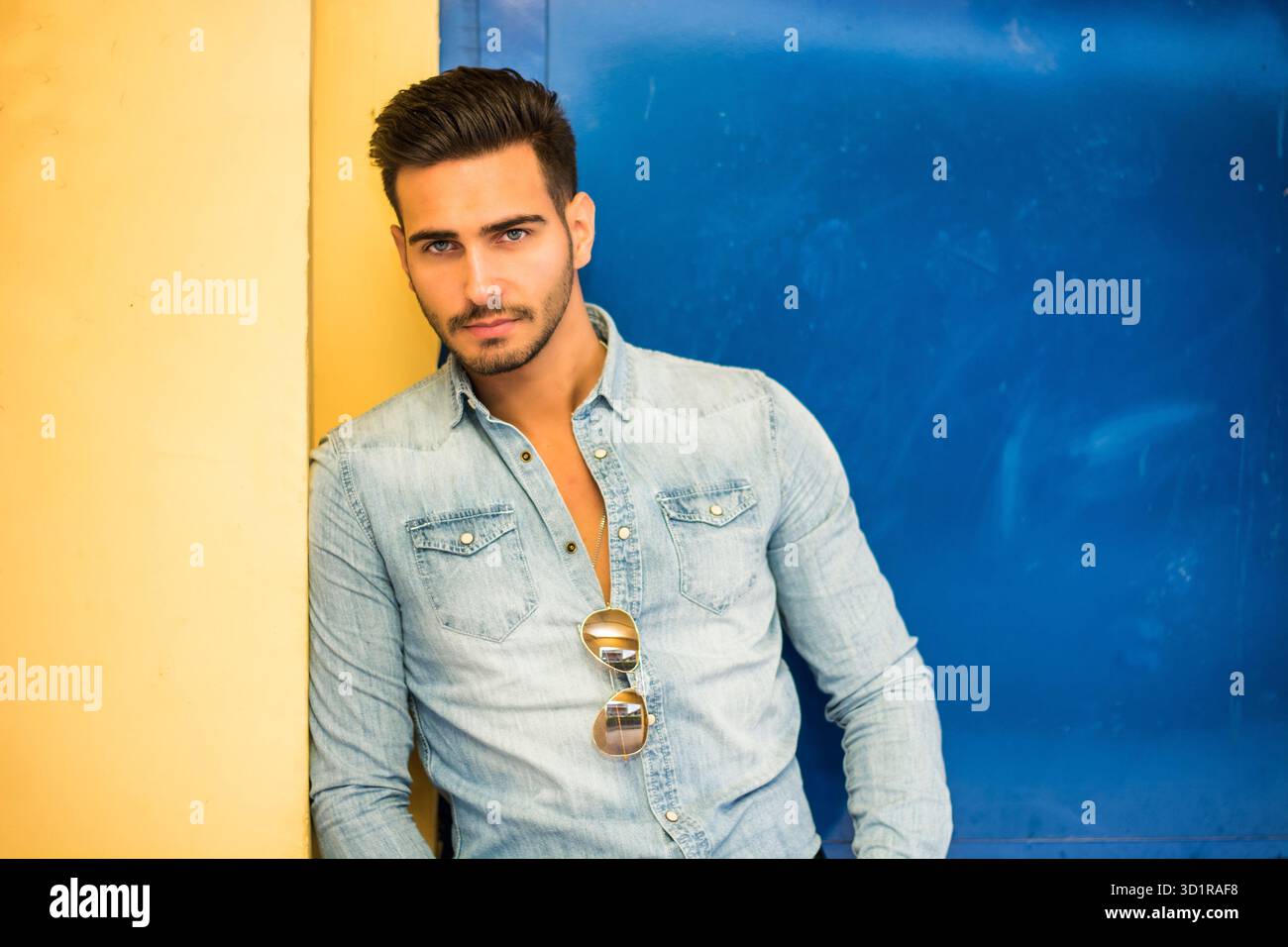 Giovane uomo seduto contro la parete colorata per esterno Foto Stock