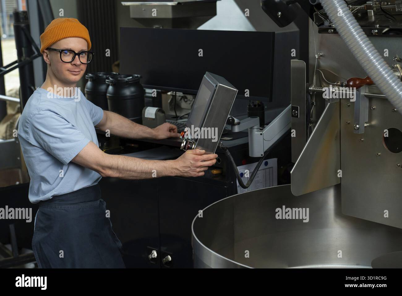 Uomo caucasico che lavora nella torrefazione del caffè, processo operativo di creazione del caffè Foto Stock
