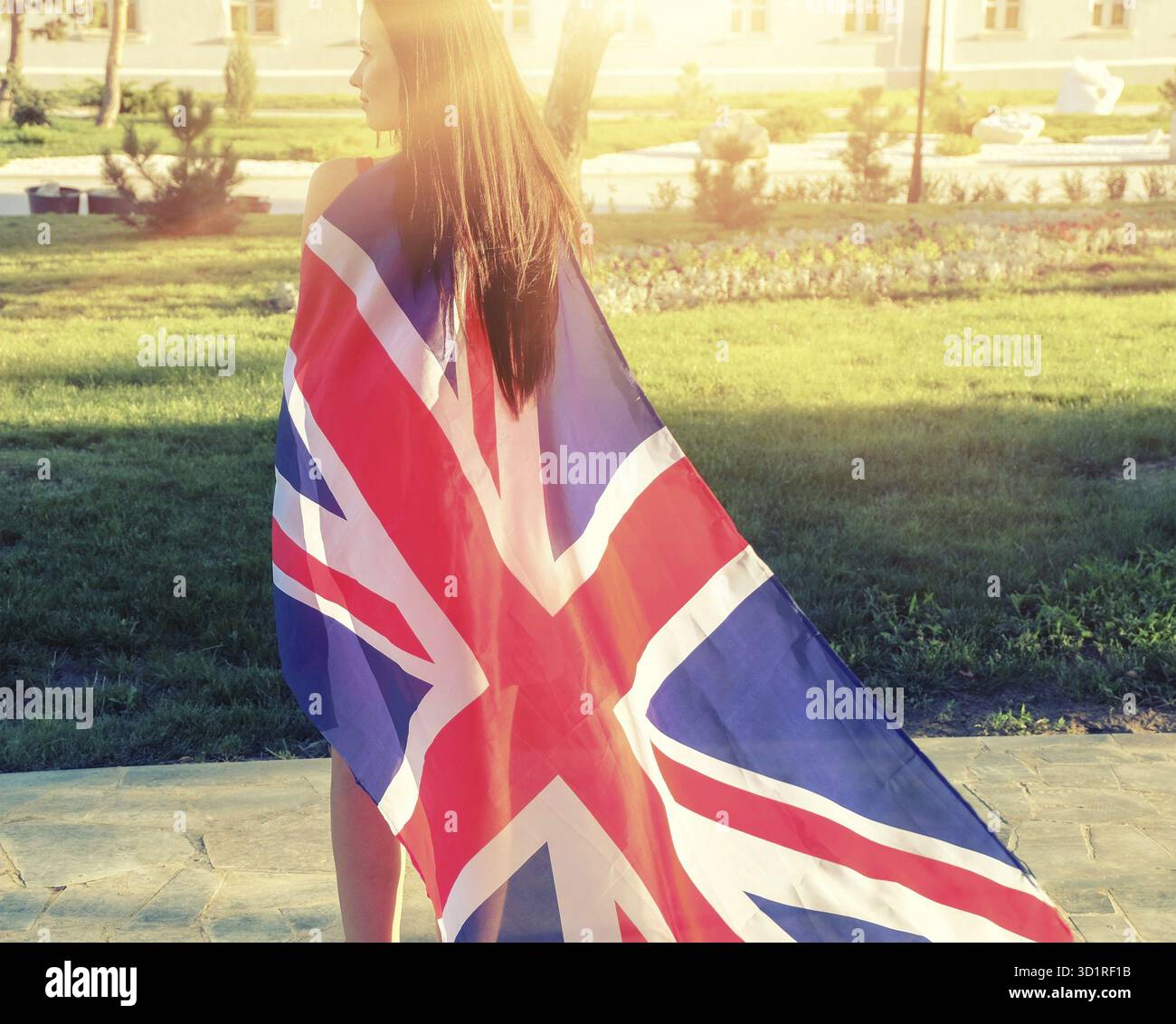 Giovane bruna deformata nella bandiera della Gran Bretagna come mantello dal retro Foto Stock