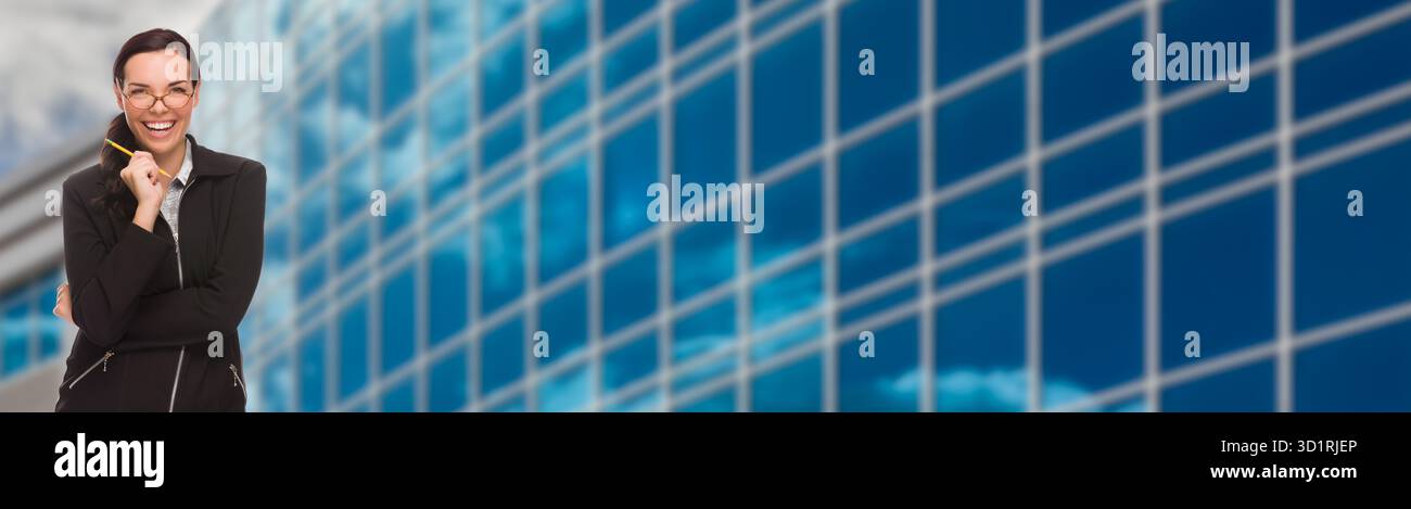 Donna d'affari che ride in corsa mista con matita davanti al banner dell'edificio aziendale Foto Stock