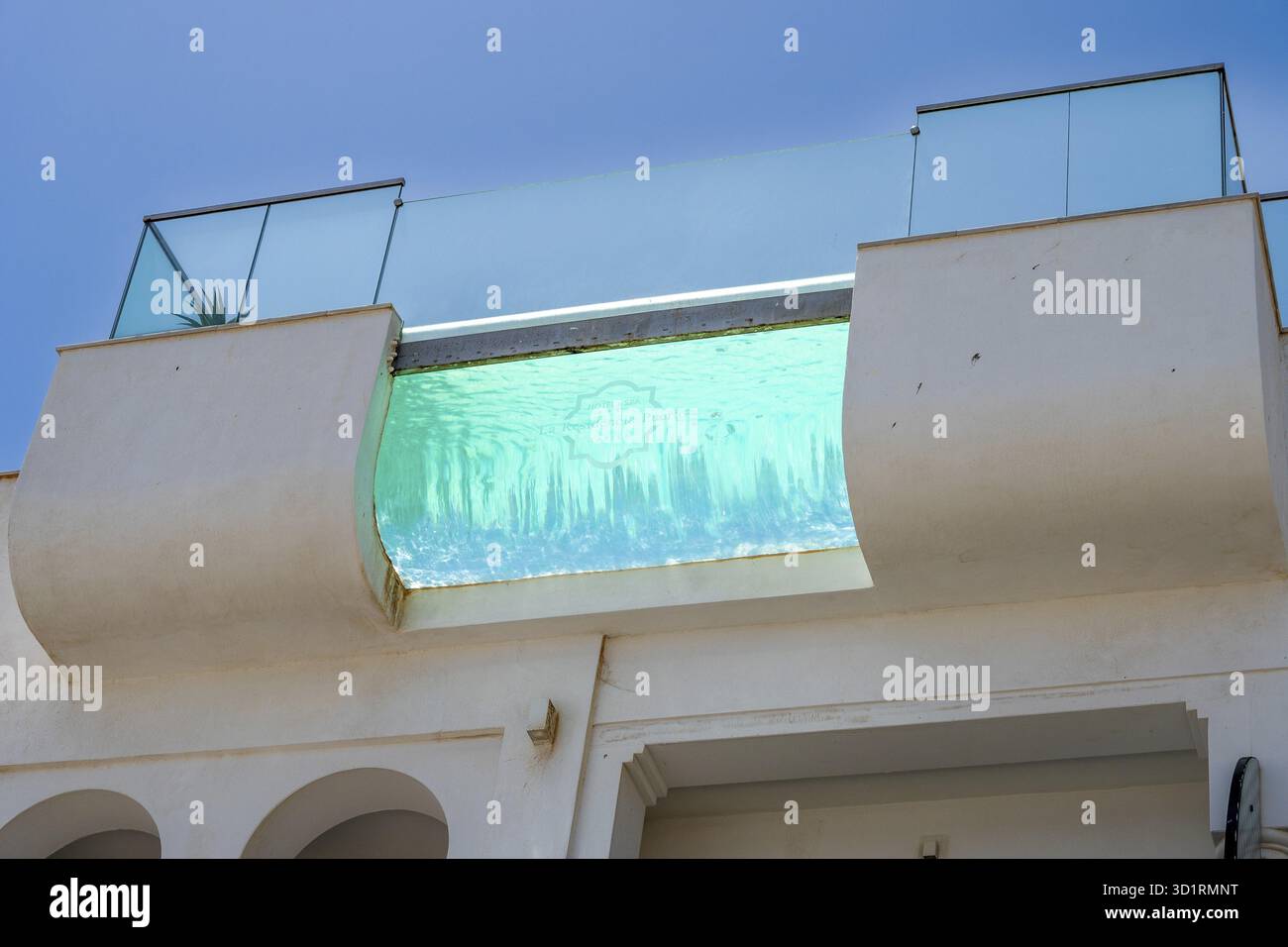 Tarifa, Cadice - Spagna â€“ 05-30-2024: Moderna piscina a sfioro in un hotel di Tarifa, con un cielo azzurro Foto Stock