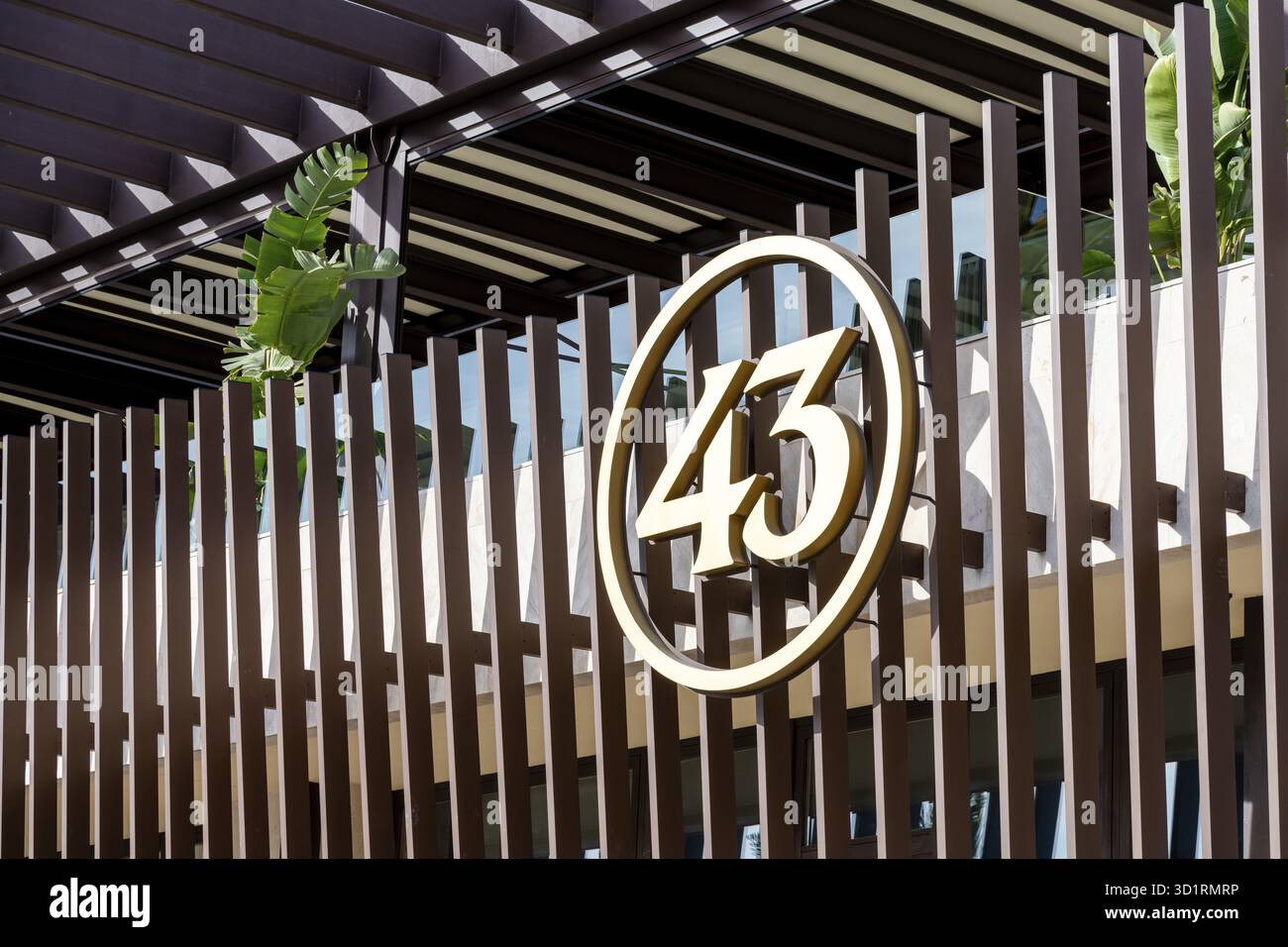 Cartagena, Murcia - Spagna - 01-16-2024: Elegante emblema dorato "43" montato su una moderna recinzione a righe presso la sede del marchio Foto Stock