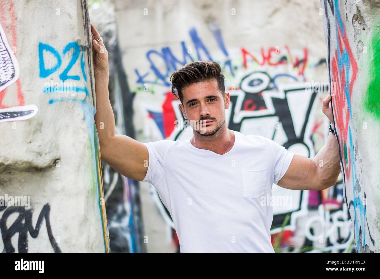 Bell'uomo giovane in una t-shirt bianca all'aperto in un ambiente urbano Foto Stock