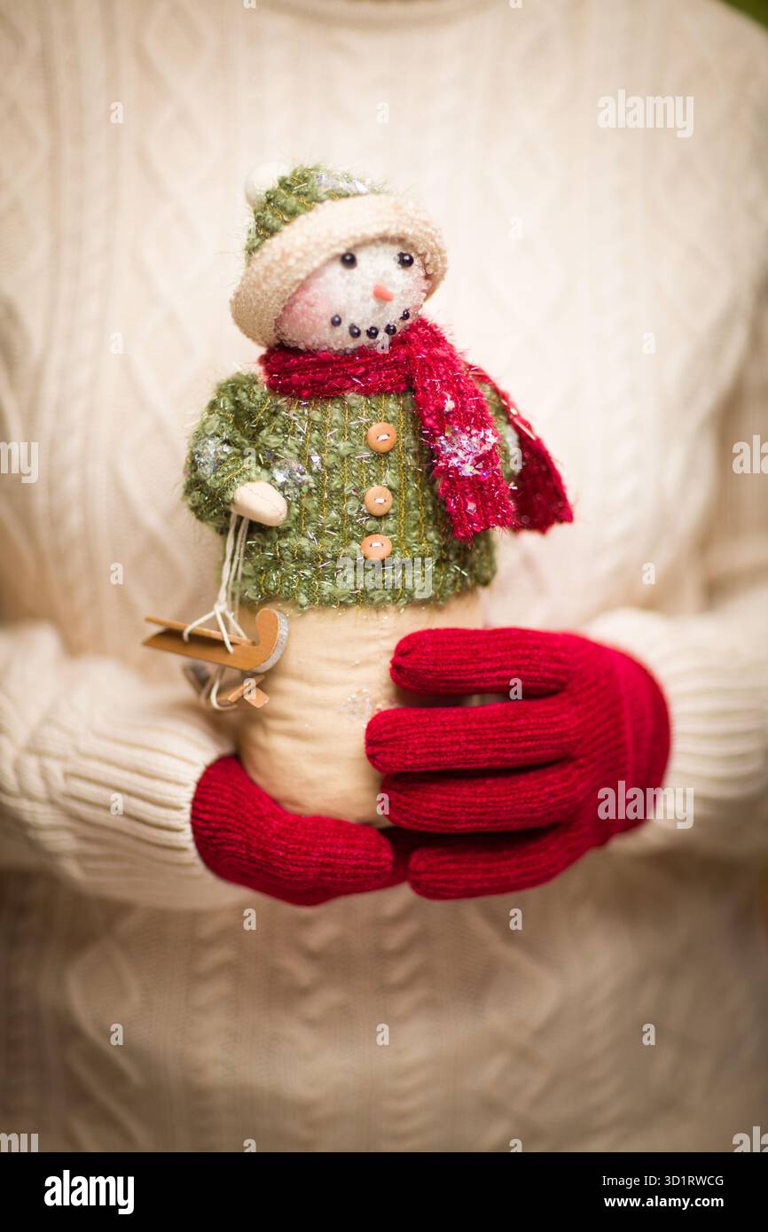 Donna che indossa i Red Mittens stagionali e tiene in mano il pupazzo di neve natalizio Foto Stock