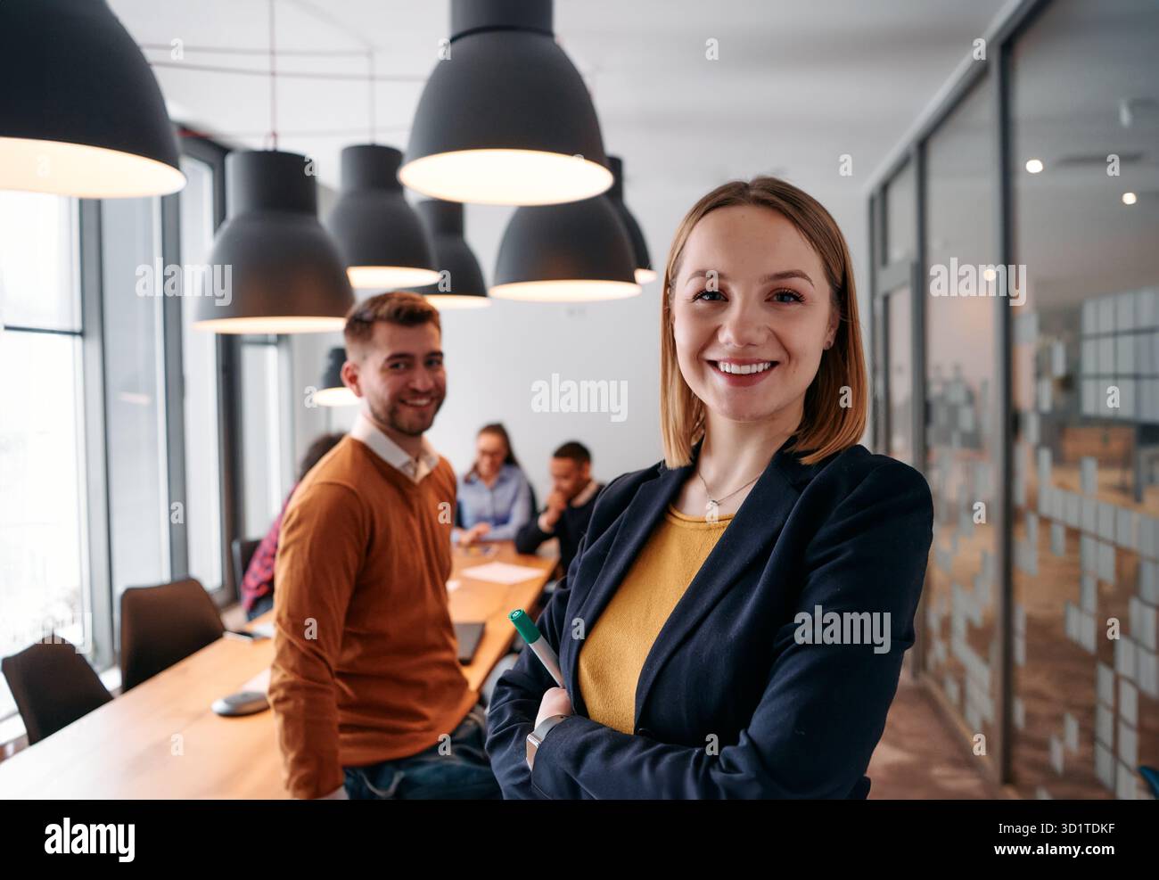 Donna d'affari bionda sicura di sé che guida il team in un ambiente moderno per l'ufficio. Foto Stock