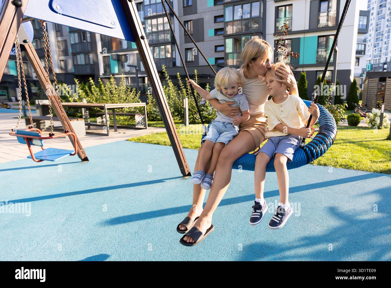 La madre ama trascorrere momenti di qualità con i suoi due figli sul parco giochi Foto Stock
