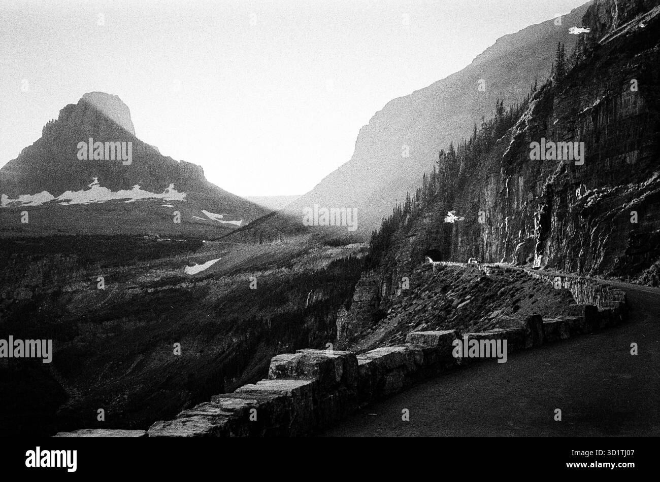 Vista in bianco e nero della Going-to-the-Sun Road che si snoda lungo le scogliere del Glacier National Park, Montana, Stati Uniti, con una spettacolare luce alpina e montana Foto Stock