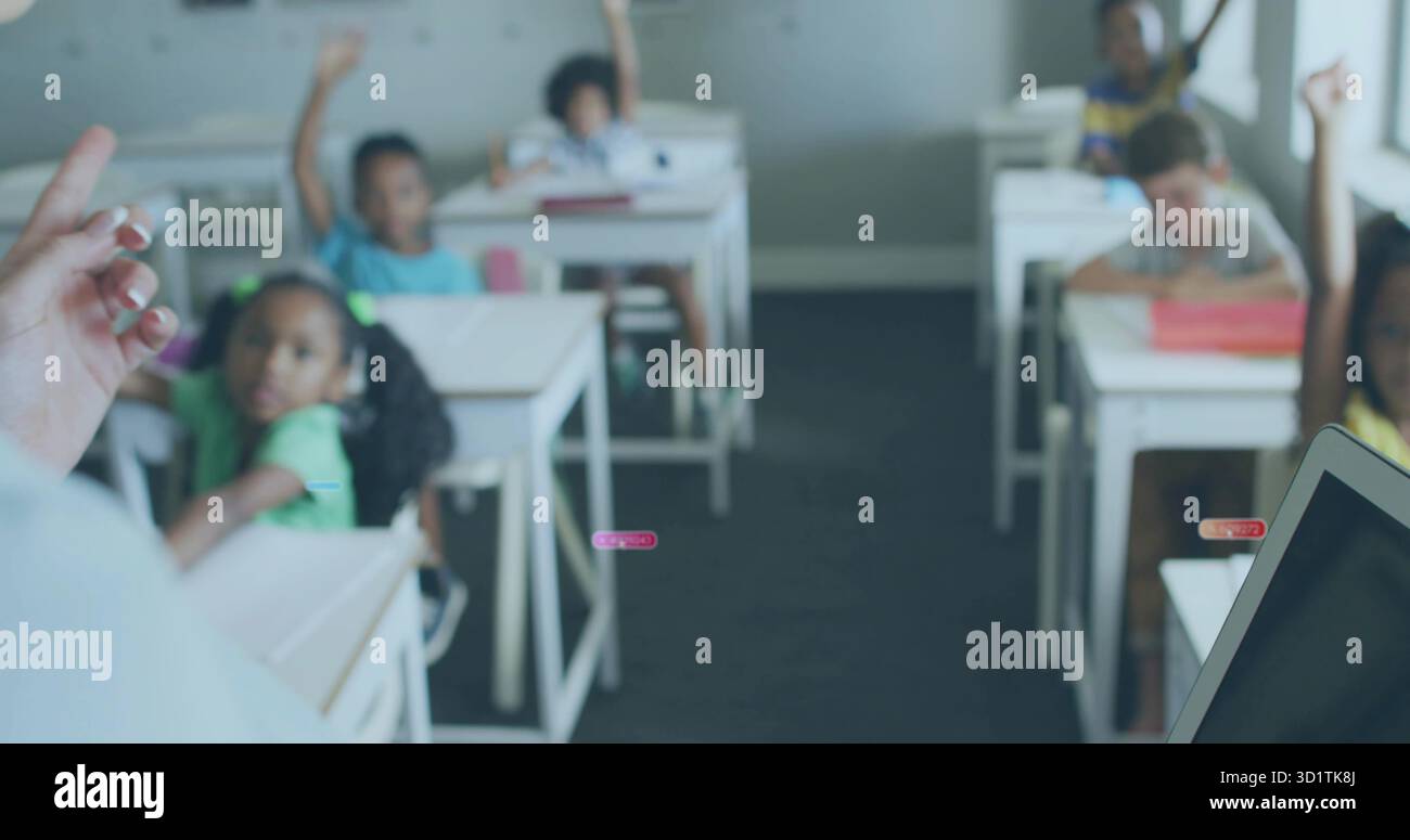 Alzare le mani gli studenti elementari seduti alle scrivanie della classe primaria di fronte all'insegnante, con un portatile Foto Stock