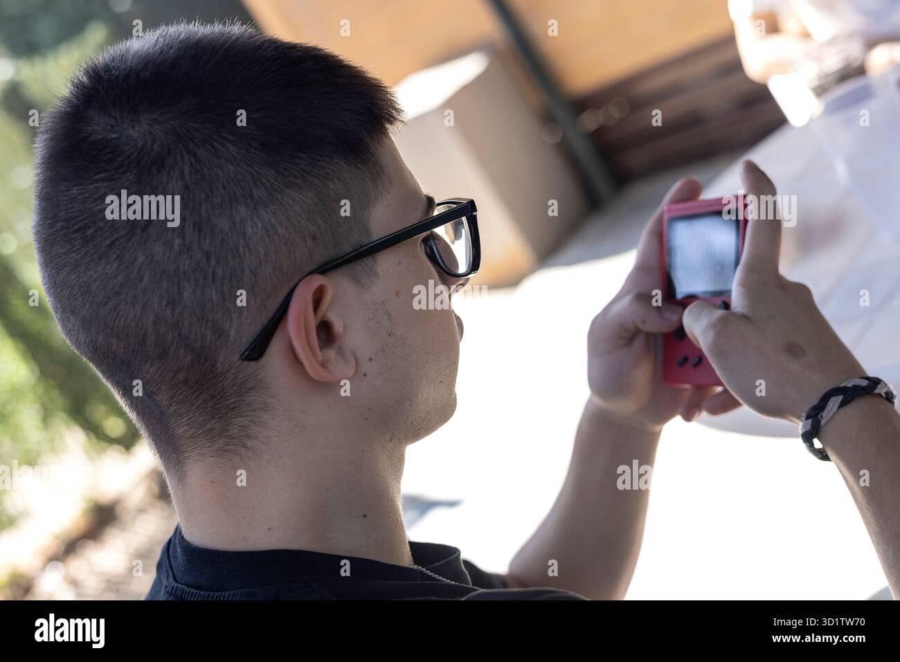 colpo inverso di un ragazzo che gioca una vecchia console rossa Foto Stock