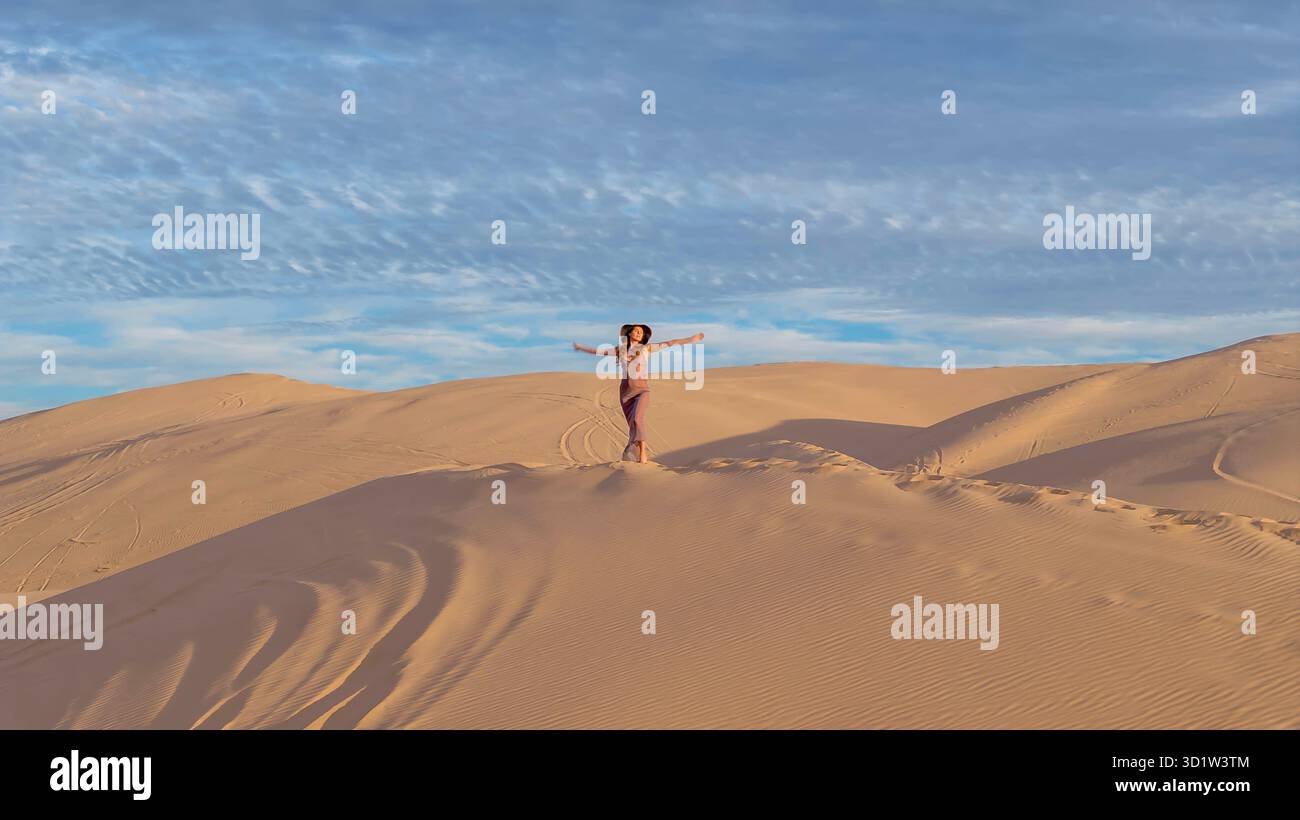 Scolpita dalla natura: La grazia della modella in mezzo alle dune di sabbia imperiali, la bellezza senza tempo della California catturata in un affascinante servizio fotografico Foto Stock