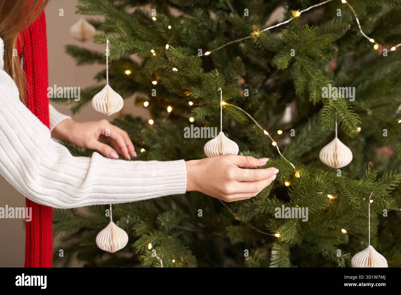 Una giovane donna veste l'albero di natale al chiuso. Ritratto delle vacanze in casa. Blogger Foto Stock