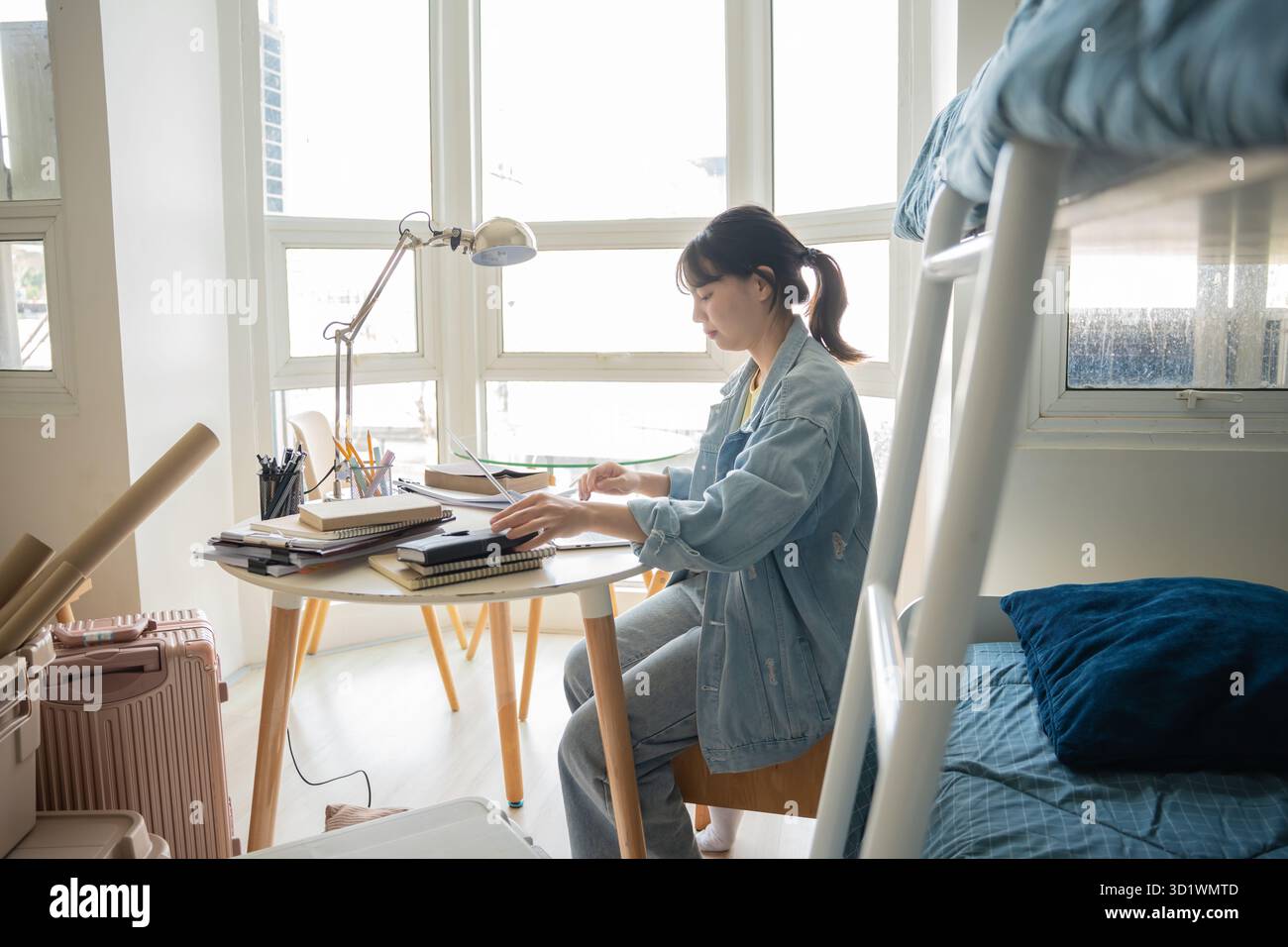 Studentessa donna asiatica seduta sul letto in dormitorio lavoro studentesco universitario o compiti a casa sul portatile nel dormitorio universitario Foto Stock