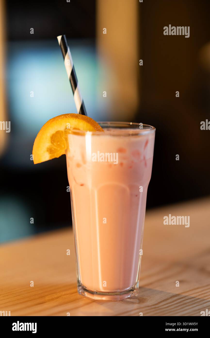Rinfrescante Milkshake rosa con fette arancioni e paglia Foto Stock