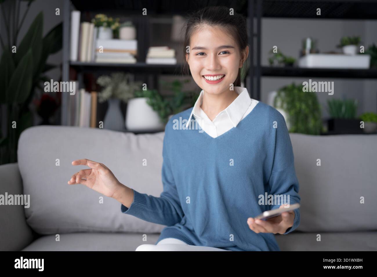 Donna asiatica che utilizza l'assistente vocale sullo smartphone a casa conversazione con assistente online chat vocale bot conversazionale ai tecnologie moderne. Foto Stock