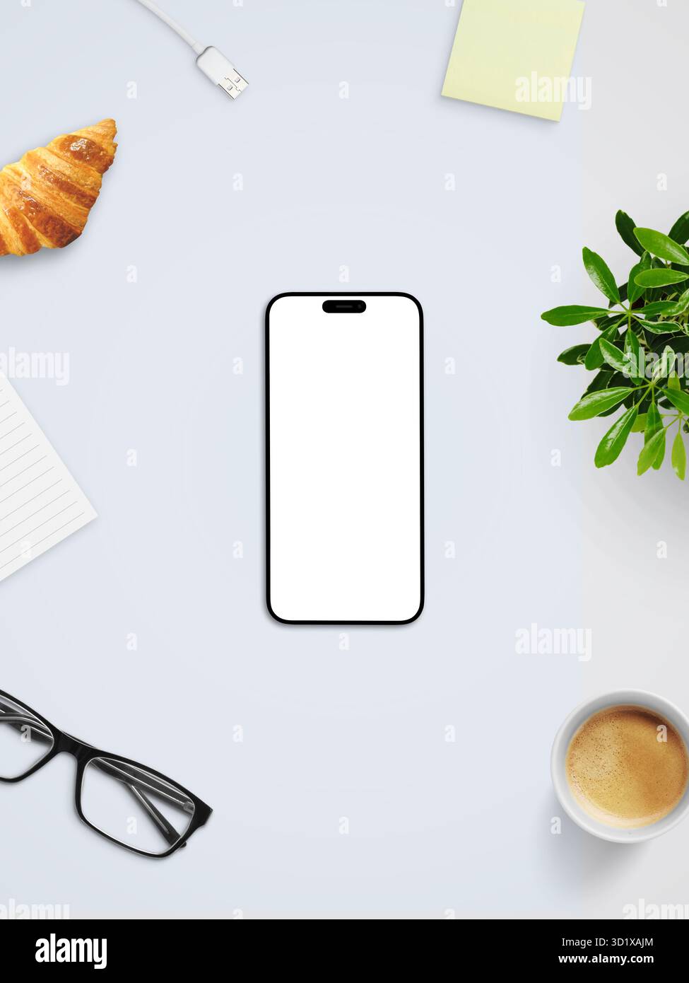 Vista dall'alto dello smartphone con schermo bianco vuoto, caffè, croissant e bicchieri sulla scrivania luminosa, che rappresenta il concetto di spazio di lavoro digitale pulito Foto Stock