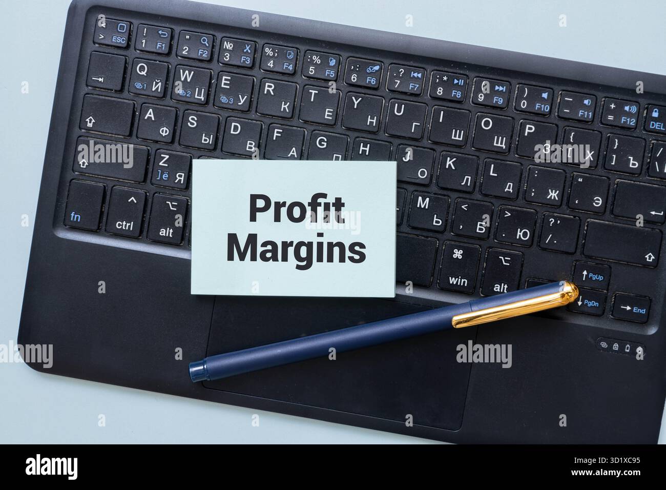 Su un tavolo di legno c'è un foglio di carta da ufficio con il testo MARGINE DI PROFITTO. Area di lavoro con calcolatrice, occhiali, penna, carta sgualcita e. Foto Stock