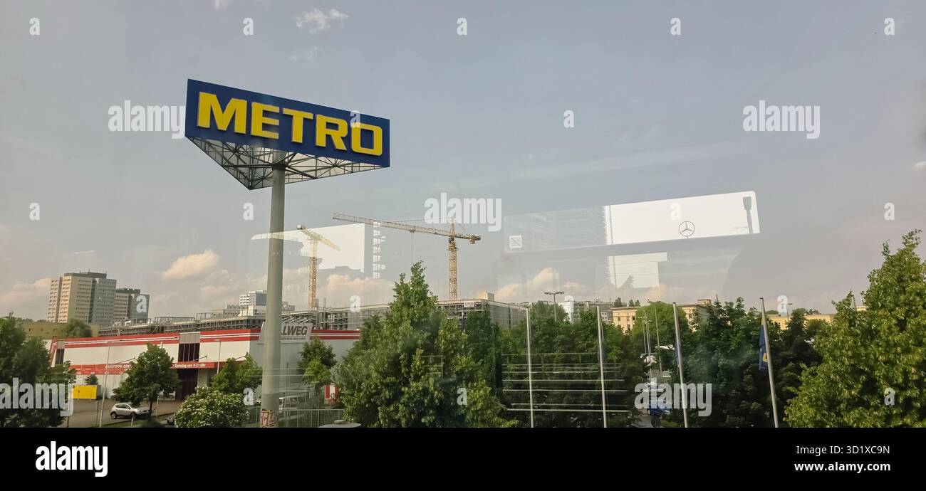 Berlino, Germania - 2 giugno 2025: L'insegna del negozio della metropolitana si erge in primo piano con il paesaggio urbano e i lavori in corso nelle vicinanze. - Immagine stock catturata con smartphone