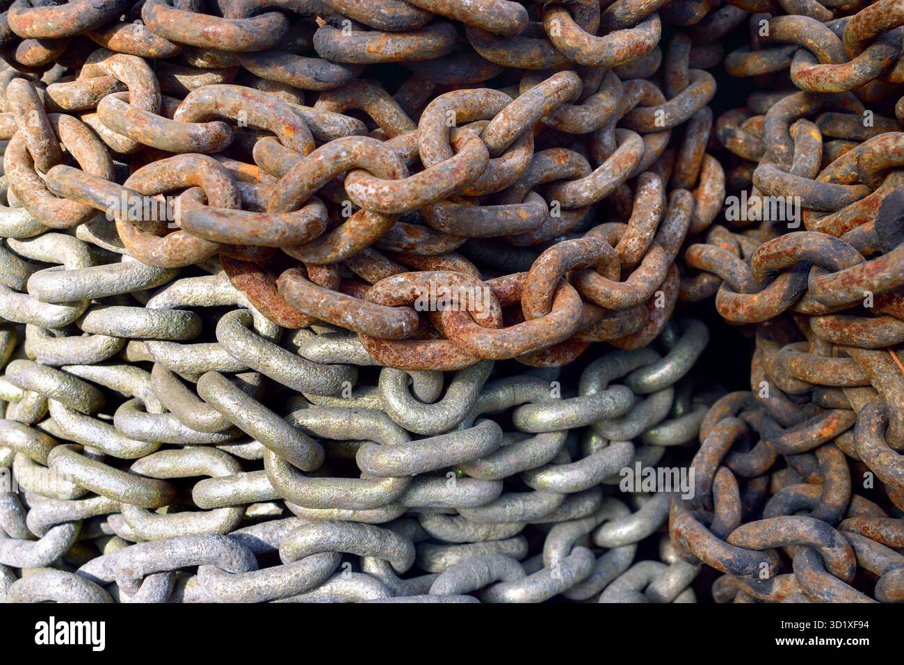 Catene di navi industriali a due colori impilate insieme, maglie in metallo arrugginito e galvanizzato. Foto Stock