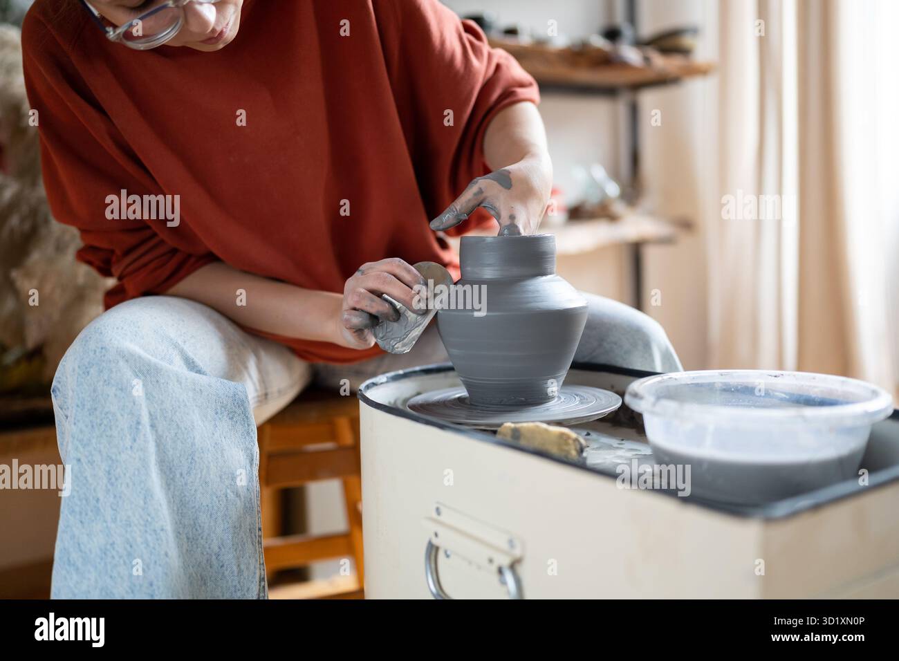 Focalizzato autonomo donna ceramista scolpisce vaso di argilla per la vendita in negozio di ceramica. Piccola impresa. Foto Stock