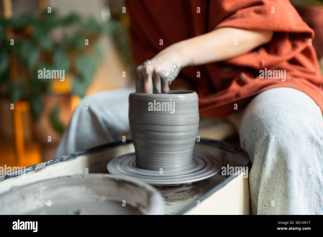 Le mani di ceramisti artigiani scolpiscono l'argilla bagnata formando il prodotto finale fatto a mano su una ruota in ceramica per l'ordinazione Foto Stock