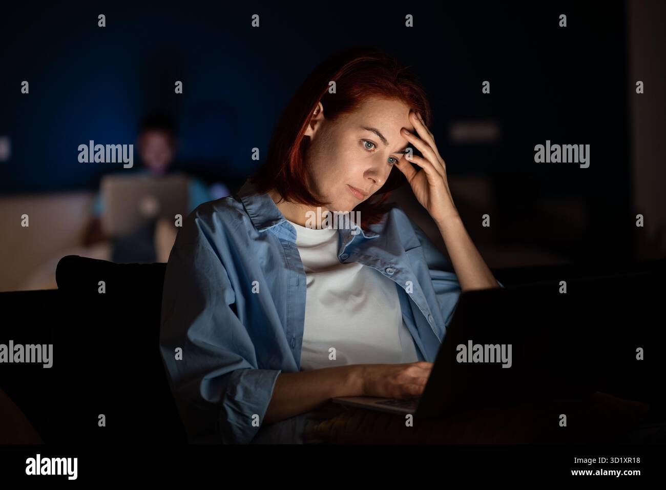 Donna freelancer di mezza età sovraccarica che lavora a casa con un computer portatile la sera tardi, la scadenza, la mancanza di sonno Foto Stock