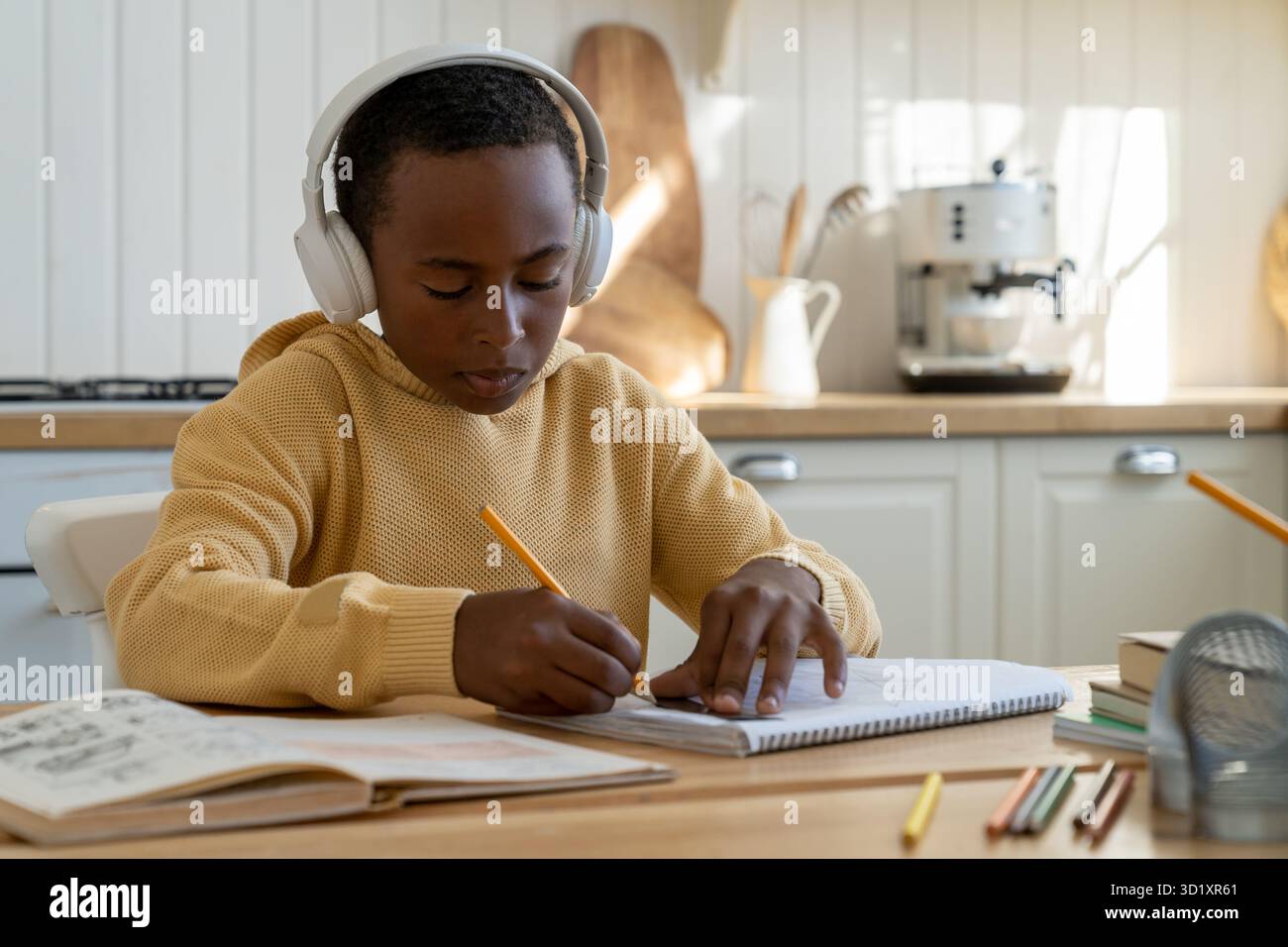 Bambino africano concentrato seduto alla scrivania lavorando su progetto di ingegneria, disegno tecnico per i bambini Foto Stock