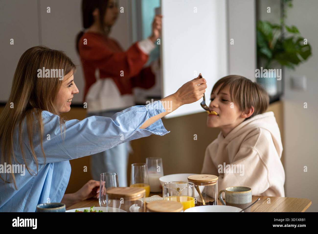 Madre felice che nutre il figlio del bambino e sorridente, mamma e bambino che si divertono mentre mangiano insieme Foto Stock