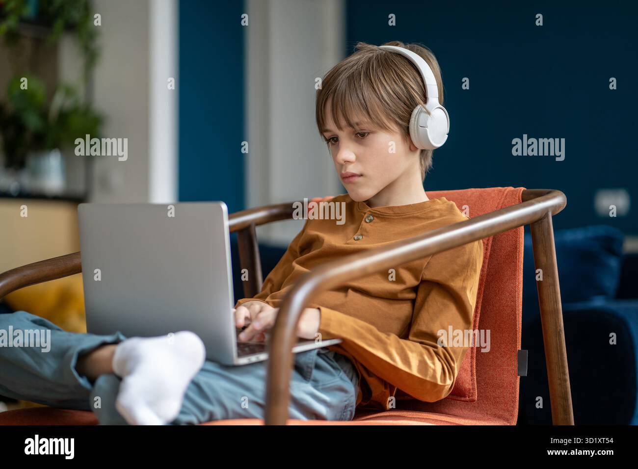 Scolaro bambino in cuffie che studia online utilizzando il notebook Foto Stock