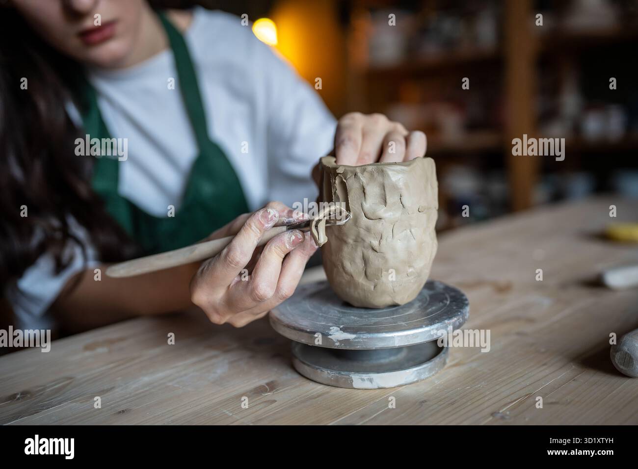 Le mani femminili utilizzano sapientemente l'anello in ceramica per raschiare l'argilla e intagliare il motivo decorativo sulla tazza Foto Stock