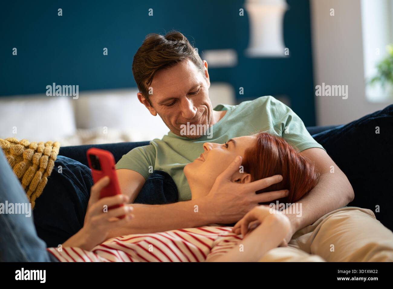 Donna sdraiata sul grembo dell'uomo. Il ragazzo abbraccia la ragazza mentre si rilassa sul divano. Intimità, vicinanza, amore, cura Foto Stock